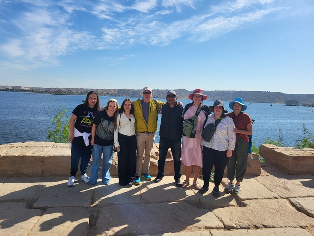 Group of people posing by the river with a distant city view.