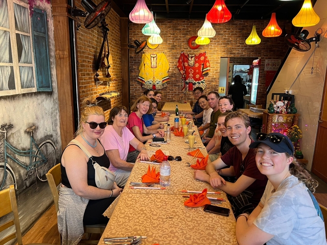       Group of people sitting at a long table with food.
  