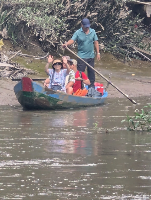       People in a small wooden boat on a river.
  
