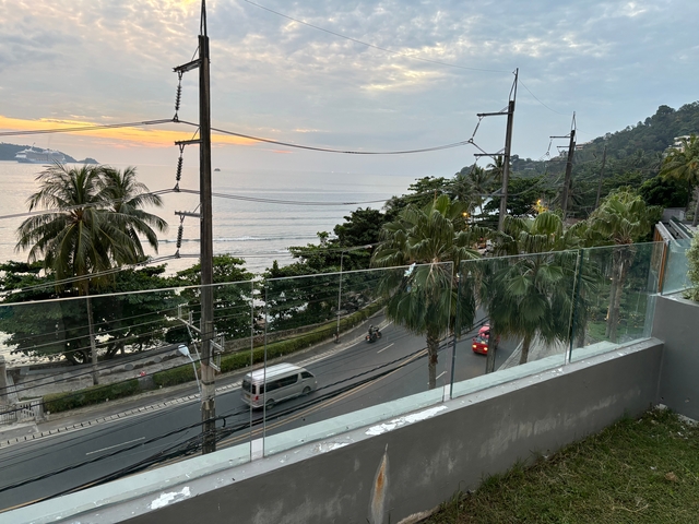 Seaside view with a sunset, road, and trees.