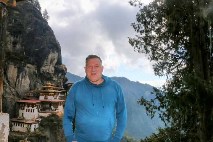       Person in front of Taktsang Monastery with mountains.
  