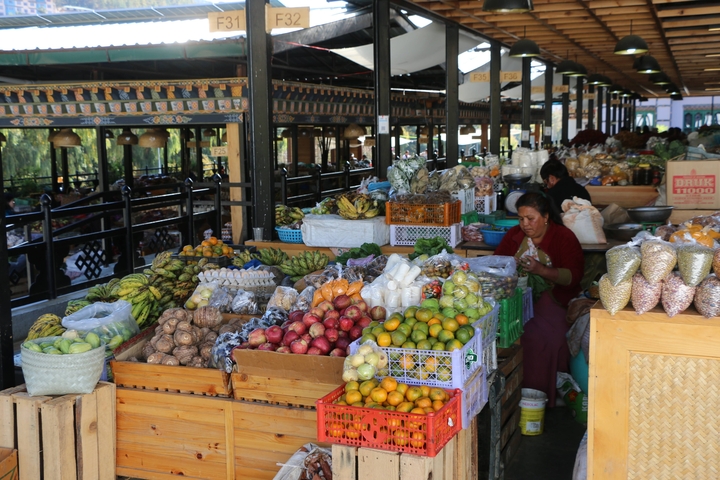       Indoor market selling fruits and vegetables with a person.
  