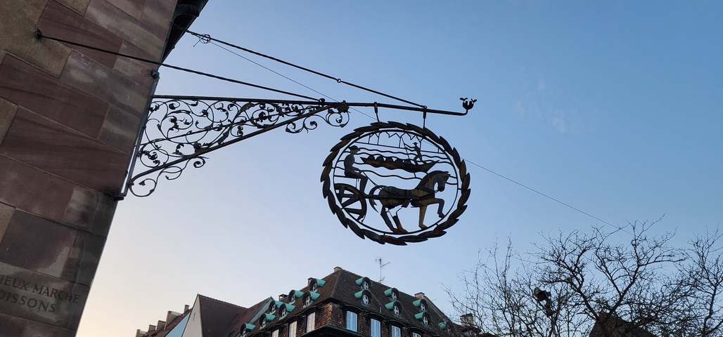       Decorative hanging sign in front of a building.
  