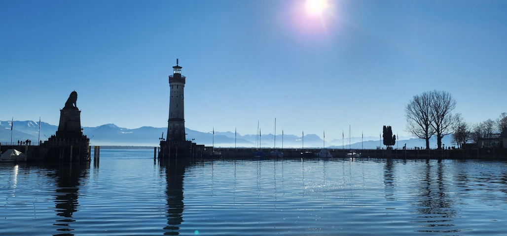       Harbor scene with lighthouse and distant mountains.
  