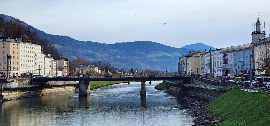       River flowing through a city with mountains in the background.
  
