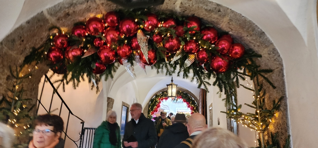       People walking through an archway decorated with Christmas ornaments.
  