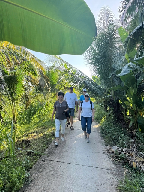 Group of people walking on a path surrounded by lush greenery.