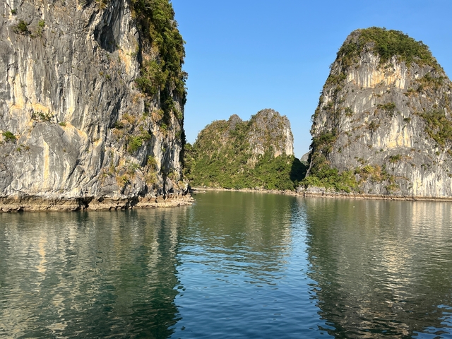       A tranquil view of a seascape with rocky islets and calm waters under a clear sky.
  