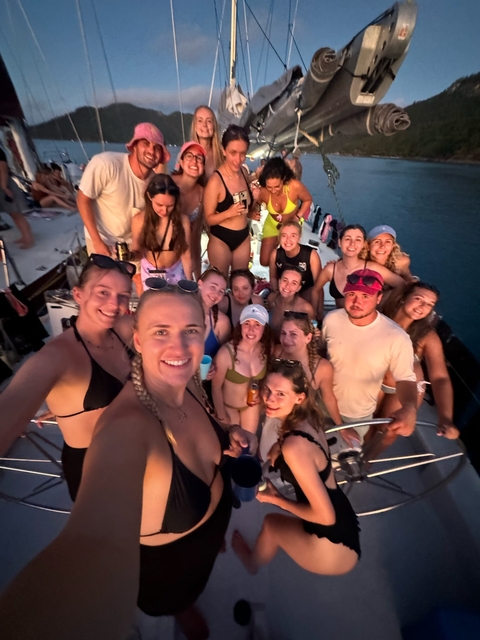       A large group on a boat, posing for a photo during sunset.
  