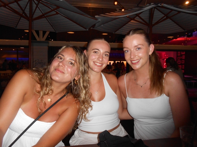 Three women posing in a nightlife setting.