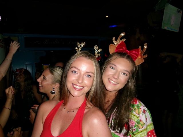 Two women wearing festive accessories posing for a photo.
