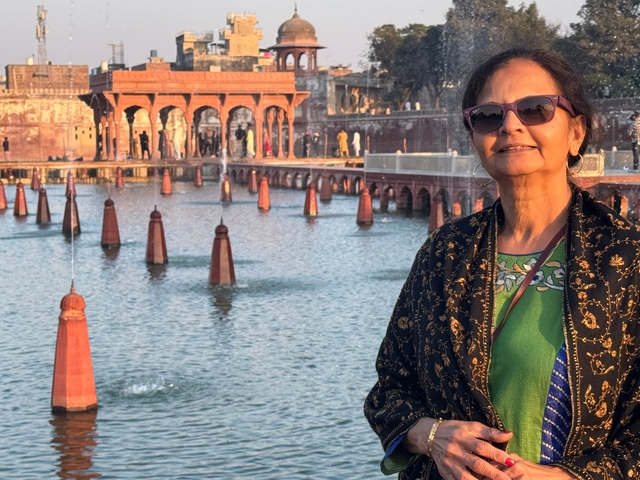 Woman posing in front of historic architecture with water feature.