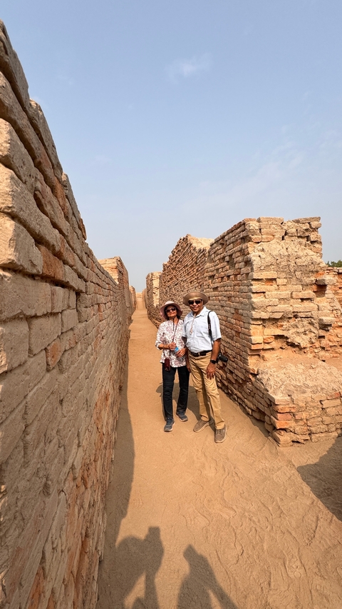 Two people posing between ancient brick walls.