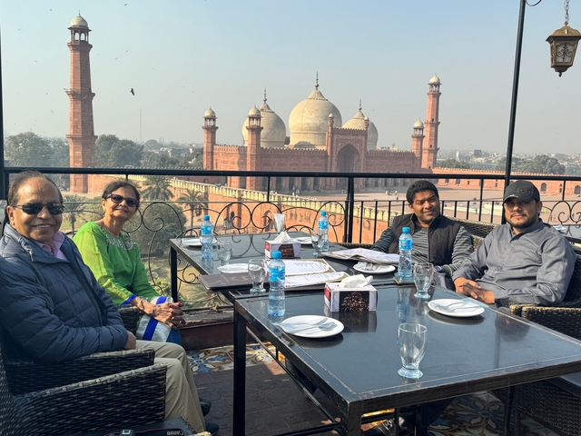 A group of people dining with Badshahi Mosque in the background.