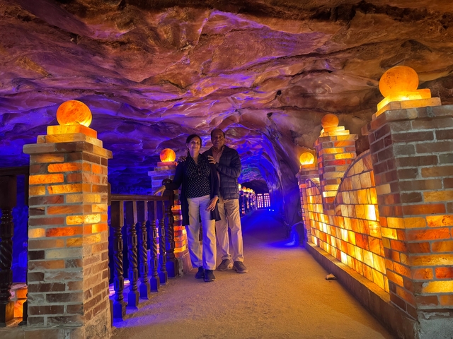       Couple posing inside a dimly lit cave with glowing salt lamps.
  