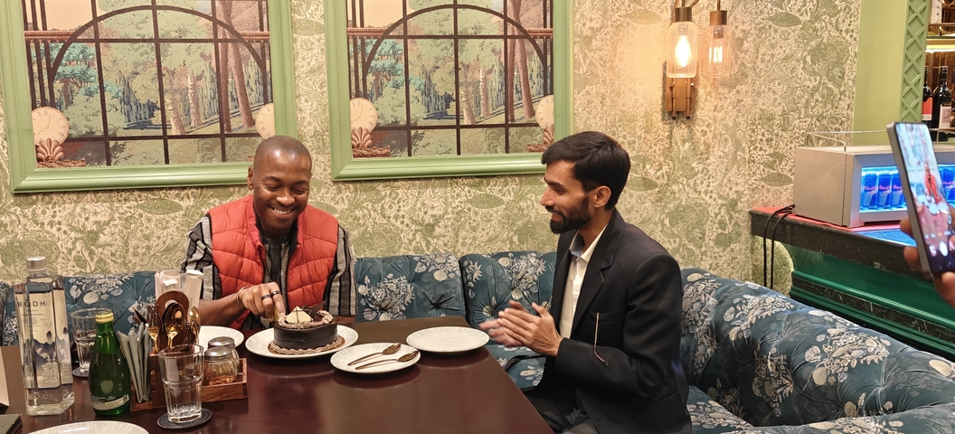       Two men sharing a table and dessert.
  