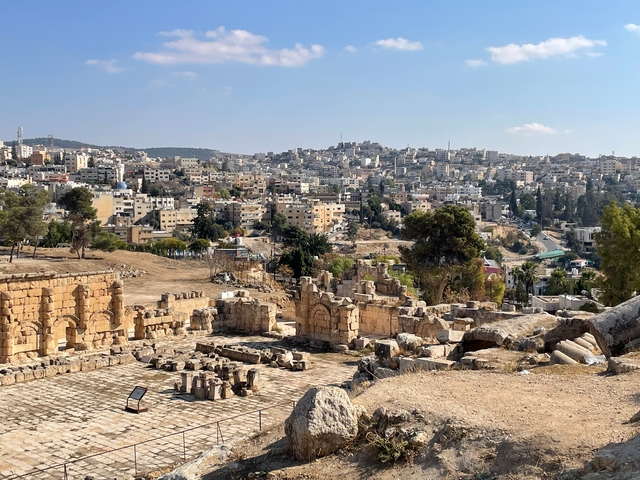       Ancient Roman ruins with city in the background.
  