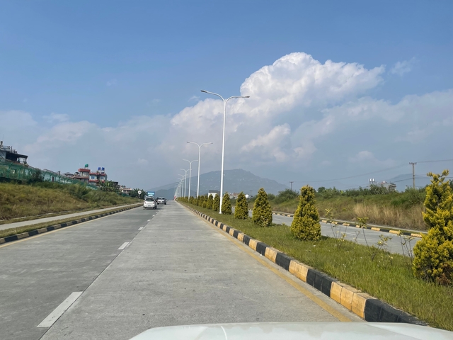 Empty highway with cars and trees during daytime.