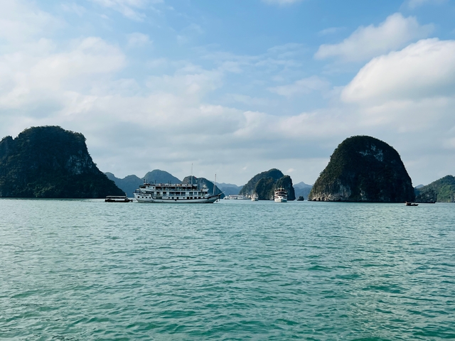       Boats on the water surrounded by limestone cliffs under a cloudy sky.
  