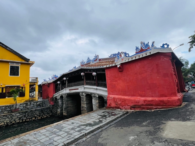       Red and yellow buildings next to a historic red bridge.
  