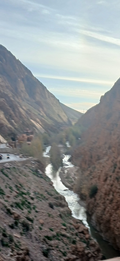 Blurry view of a valley with a river and mountains.