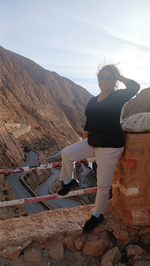 Person posing with scenic rocky valley in background.