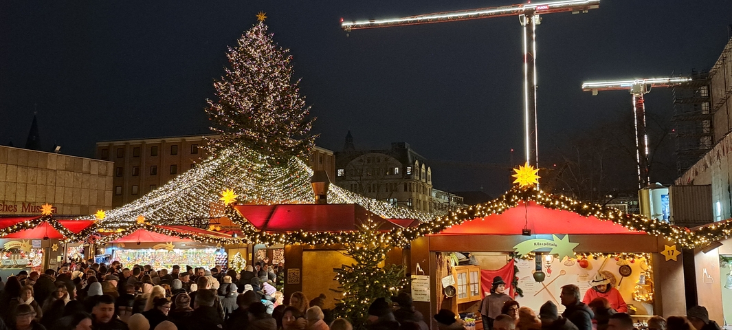       Christmas market with festive lights and crowd.
  