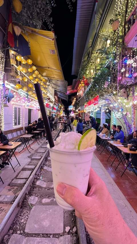 Busy street with vibrant lights and seated people at night.