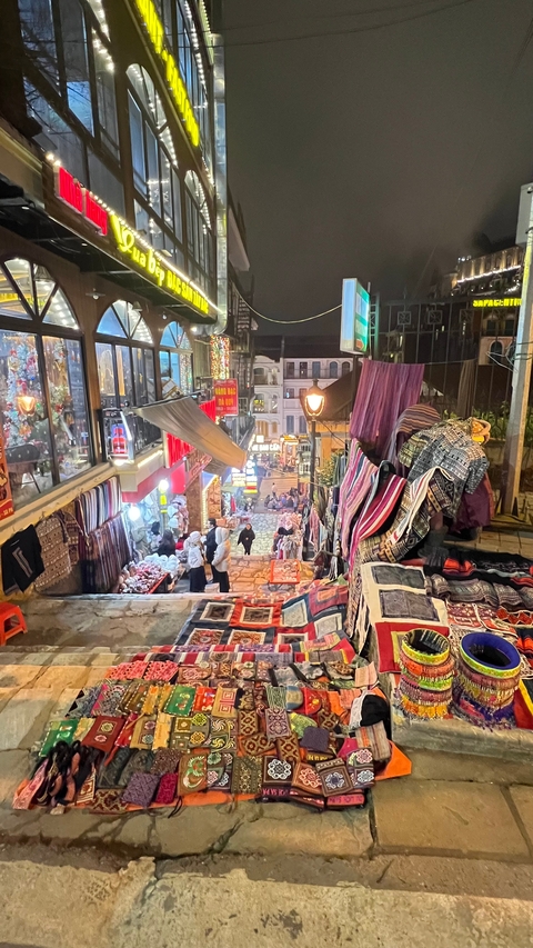 Busy market alleyway with textiles and decorations.