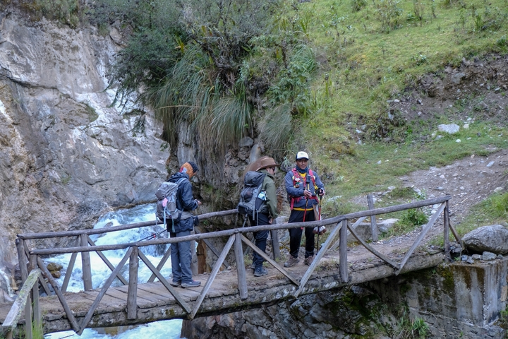       People hiking on a wooden bridge over a waterfall.
  