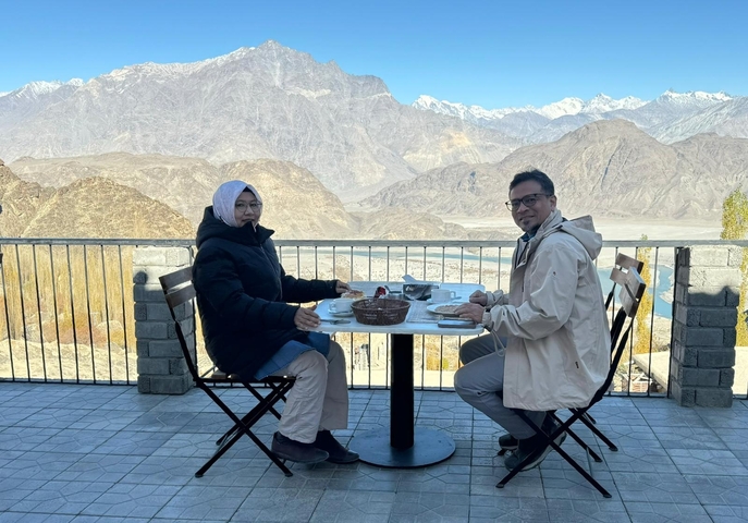 Couple having a meal on a terrace overlooking mountains.