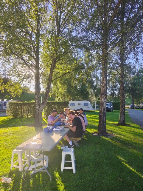 Outdoor picnic with people sitting at a table with caravans nearby