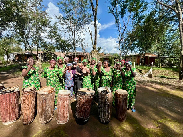       Group of women in traditional attire with drums outdoors.
  