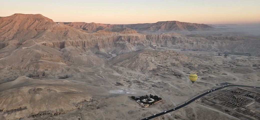       Aerial view of a vast desert landscape with a hot air balloon.
  