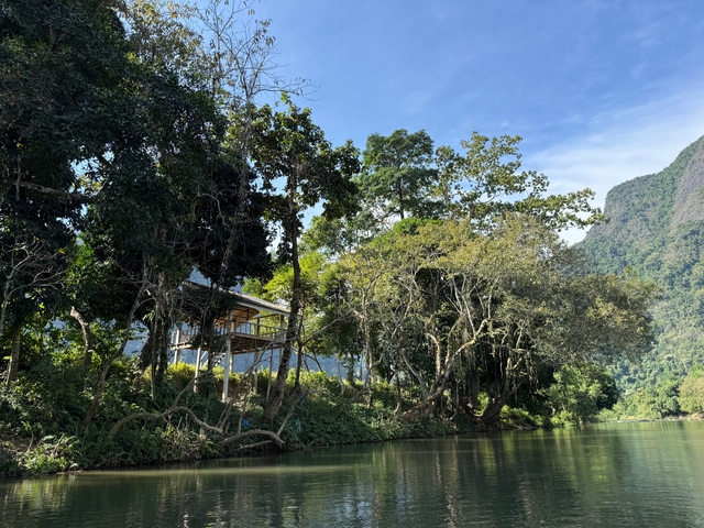 River scenery with trees and a small house.