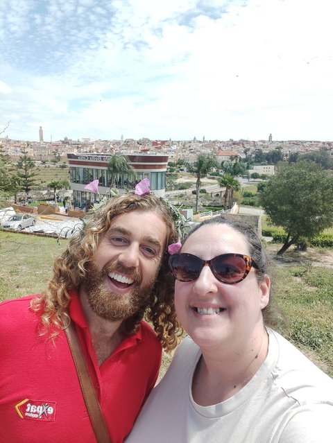 Two people smiling with a city view in the background.