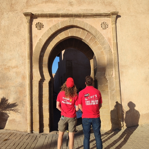 Two people standing in front of a large arched entrance.