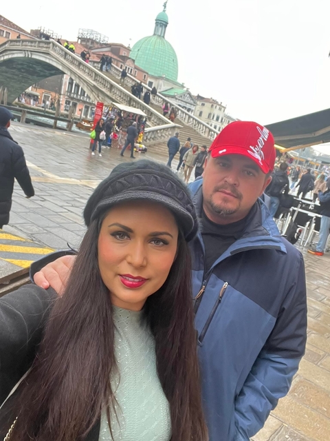 Two people posing in an urban area with crowds in the background.