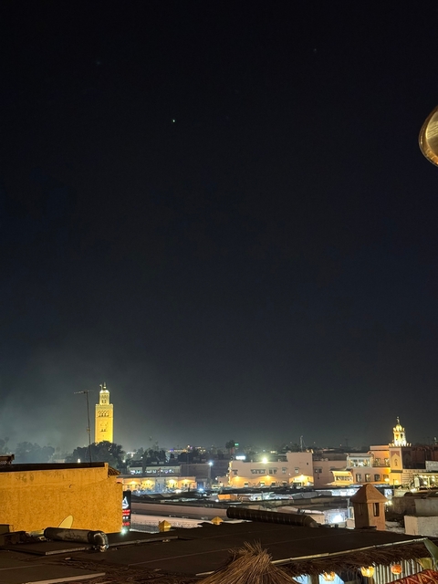       Night view with a minaret in silhouette against a dark sky.
  