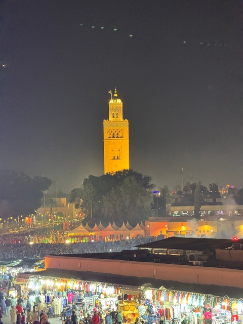       Illuminated minaret tower at night in a cityscape.
  