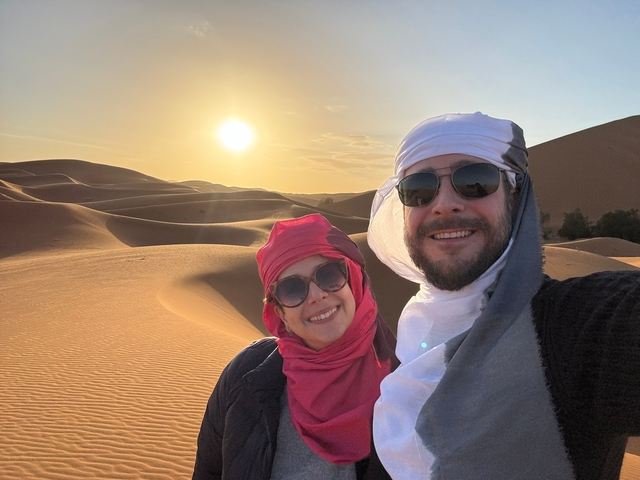       Couple posing with sunset over sand dunes.
  