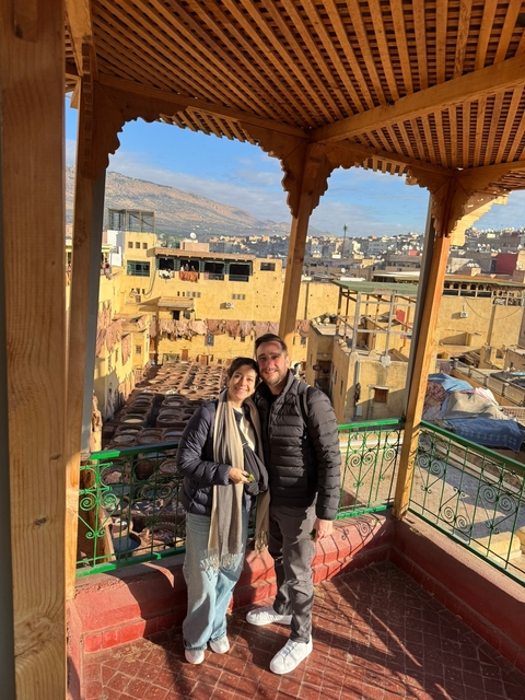       Couple posing on a rooftop with a view of the city and tanneries.
  