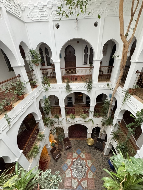       Interior view of a traditional Moroccan riad with lush greenery.
  