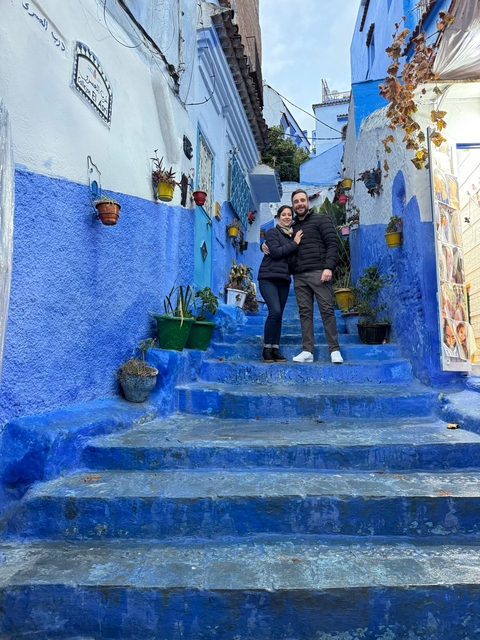      Couple posing on blue-painted steps in Chefchaouen.
  