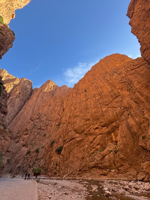       Tall rocky red cliffs rising into a blue sky.
  