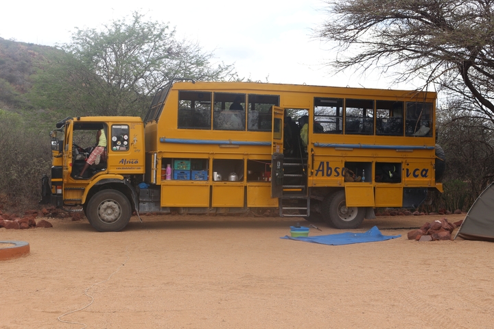Safari truck parked outdoors with camping gear visible.