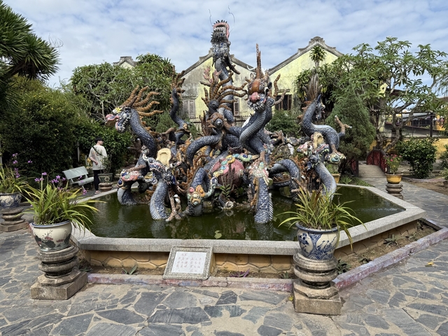 Elaborate fountain sculpture with dragon motifs in a garden setting.