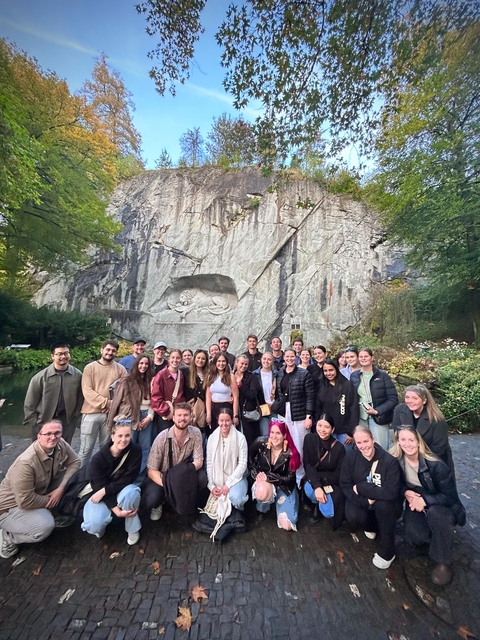 Group of people in front of the Lion Monument, carved into the cliffside.