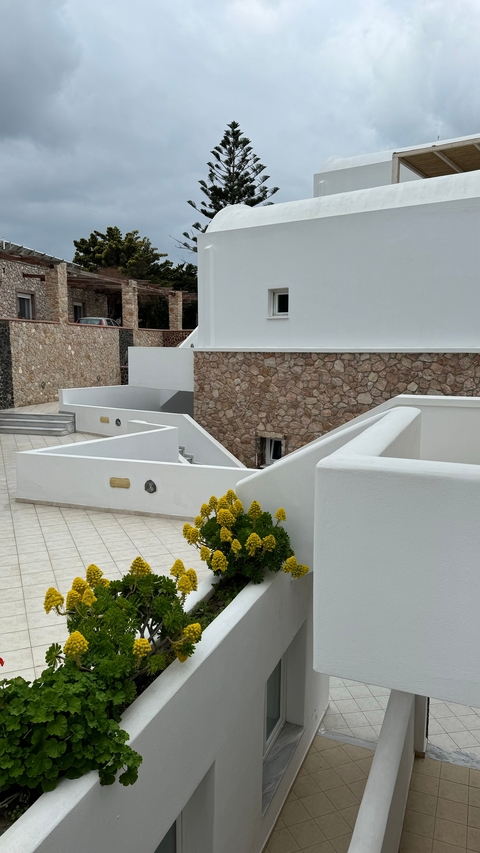       Exterior of a modern building with white walls and stone detail.
  