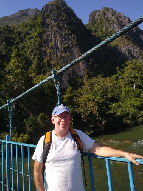       Person on a bridge with a mountainous background.
  